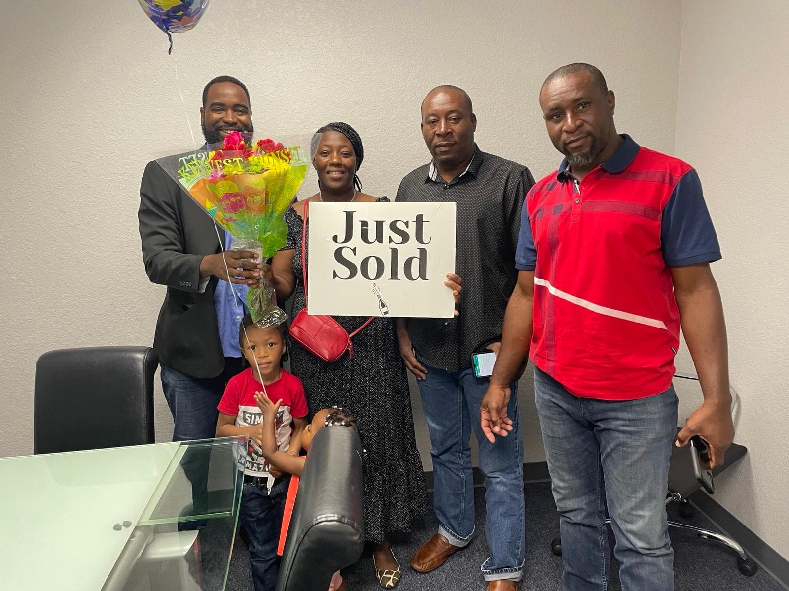 A family holding a Just Sold sign and flowers with Paul