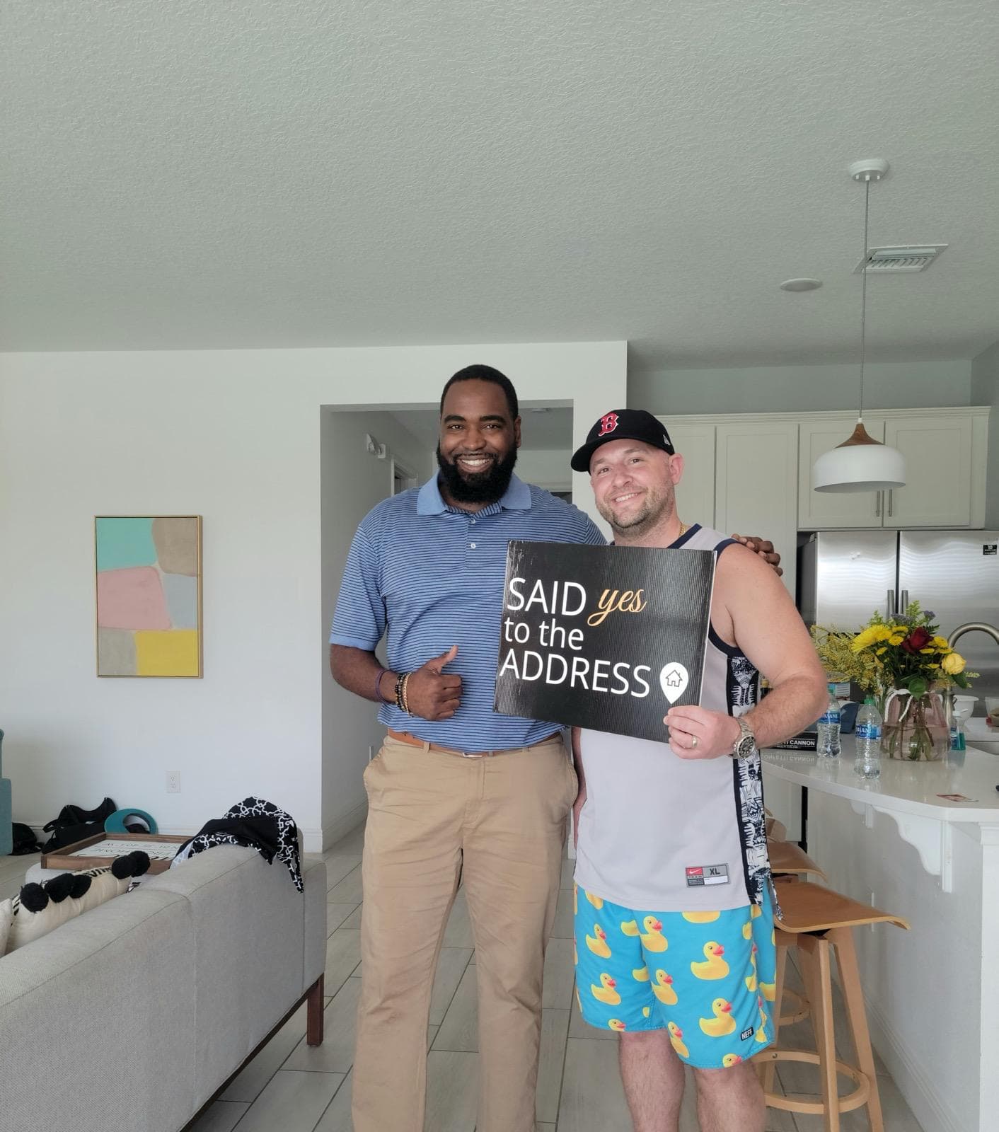 Paul with a client holding a Said Yes to the Address sign in their new home